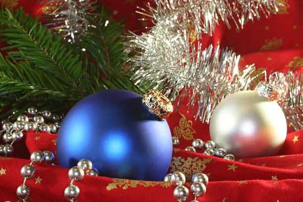 blue and silver Christmas balls with fir trees on red fabric