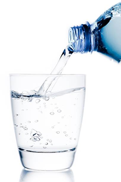 istock filling a glass with water trough little blue bottle 523402374