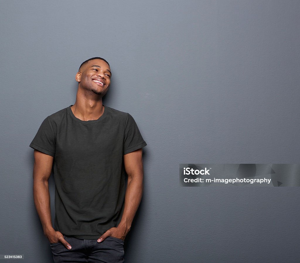 Portrait of a cheerful young man smiling Portrait of a cheerful young man smiling in gray background T-Shirt Stock Photo