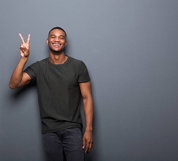 istock Young man smiling showing hand peace sign 523415387