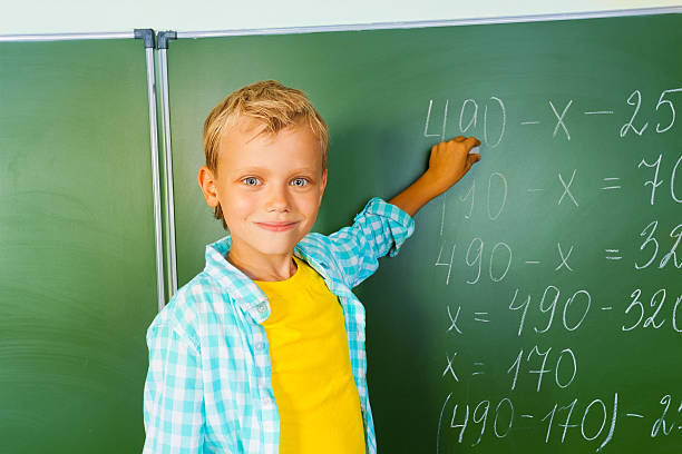 istock Boy with chalk stands near blackboard and looking 523431703