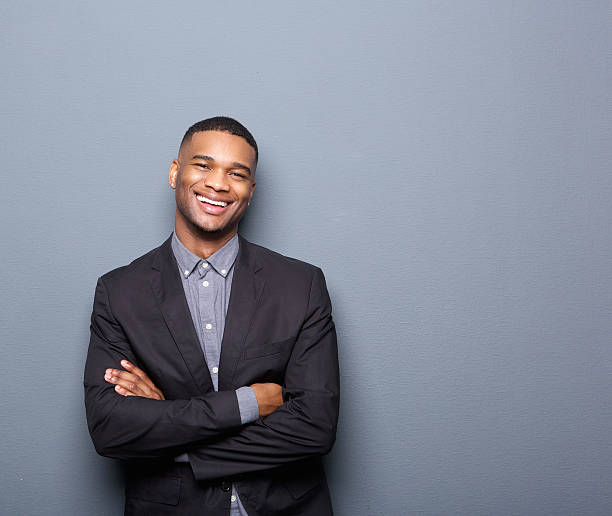 homem de negócios jovem feliz sorrindo com braços cruzados - african descent casual clothing looking at camera - fotografias e filmes do acervo