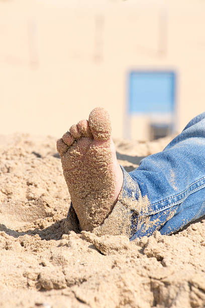 istock Little feet in the sand wearing jeans 523432473