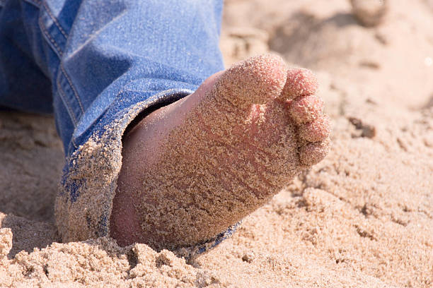 istock Little feet in the sand wearing jeans 523432479