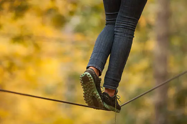 Girl walking along a tightrope in the trees.