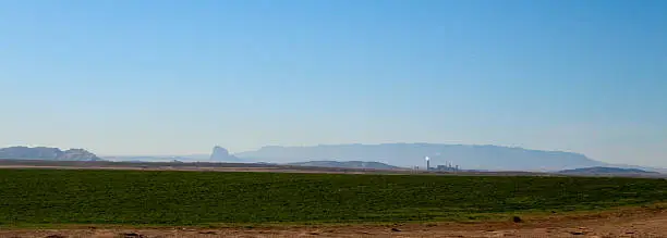 Coal fired power plant and shiprock in the distance over farmland in New Mexico