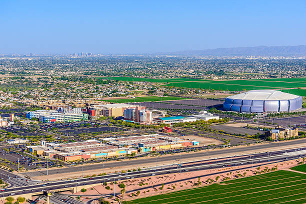 An outlet mall, hotels, and various other shopping and entertainment facilities in Glendale Arizona (a suburb of Phoenix, Arizona). Phoenix skyline is visible in the distance on the horizon. The University of Phoenix Stadium is home to the 2015 championship game XLIX.