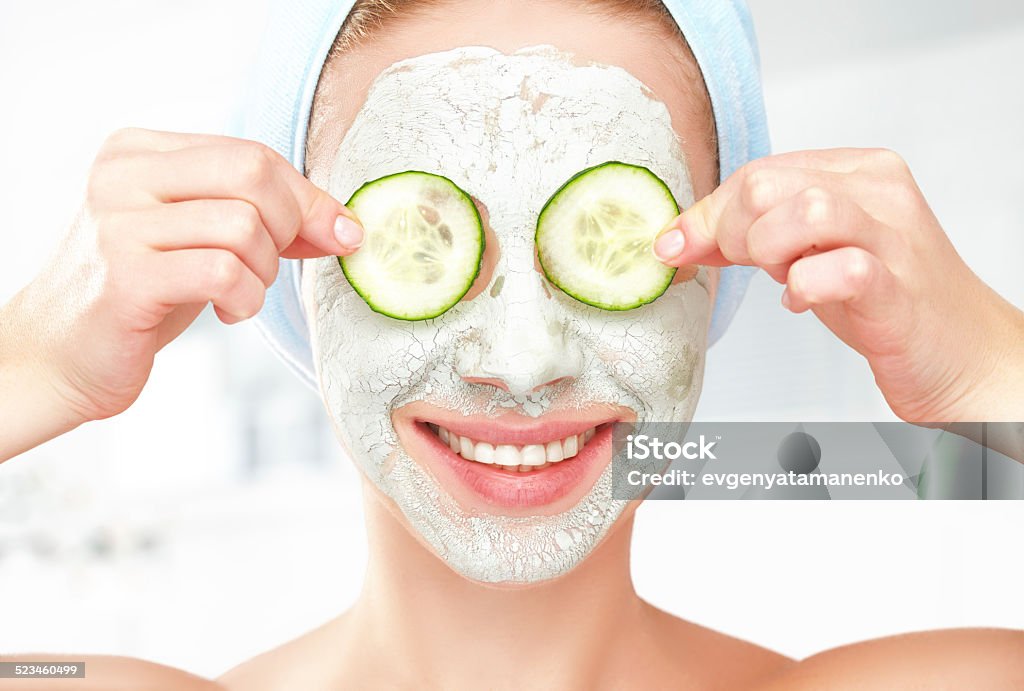 Funny young girl with mask for skin face and cucumbers Funny young girl with a mask for skin face and cucumbers on eyes Cucumber Stock Photo