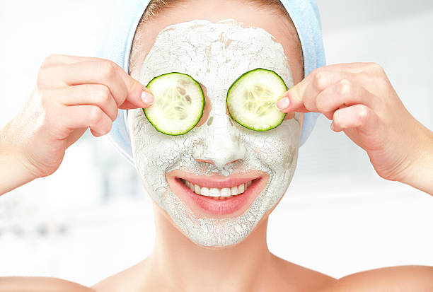 engraçado jovem com máscara de pele rosto e pepinos - facial mask spa treatment cucumber human face imagens e fotografias de stock