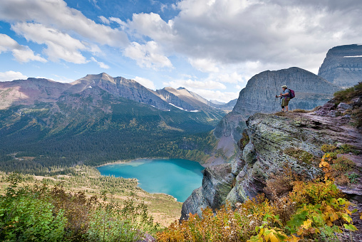 This woman hiker is looking down on Lower Grinnell Lake while hiking the Grinnell Glacier Trail in Glacier National Park, Montana, USA.