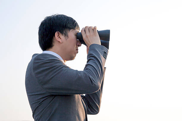 istock Asian businessman using binoculars during sunset being isolated 523478546