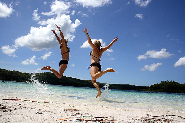 Holiday Fun Girls jumping at Lake McKenzie fraser island stock pictures, royalty-free photos & images