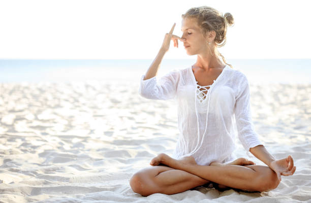 istock Woman practices pranayama in lotus pose on the beach 523480402