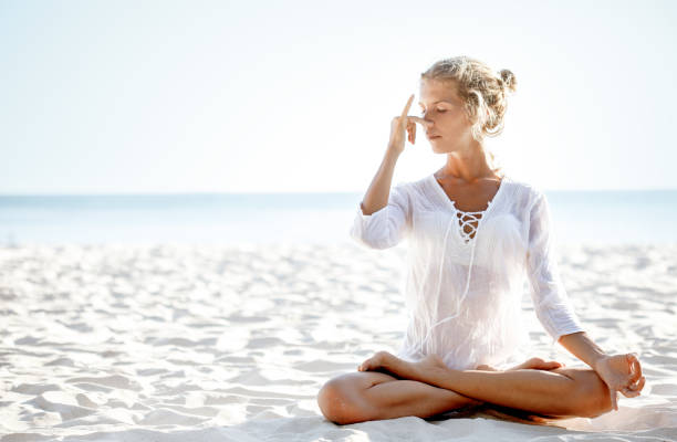 Woman practices pranayama in lotus pose on the beach