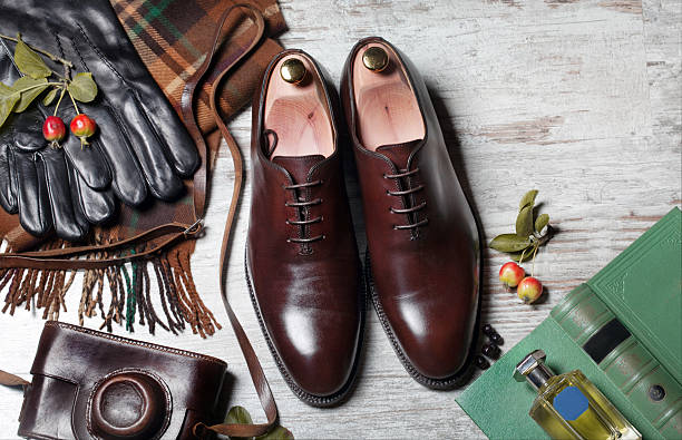 Male Clothing  Accessories  male brogue shoes Featuring Typical Male Clothing and Accessories Still life with brown boots, leather belt and camera on aged textured boards A pair of luxury brown shoes close up on wood background brogue photos stock pictures, royalty-free photos & images