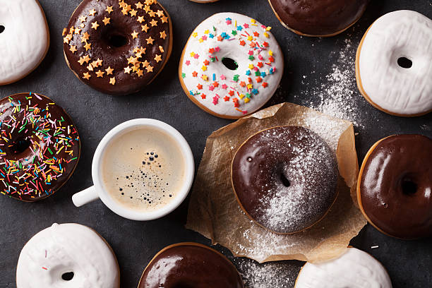 Colorful donuts and coffee cup Colorful donuts and coffee on stone table. Top view donuts stock pictures, royalty-free photos & images