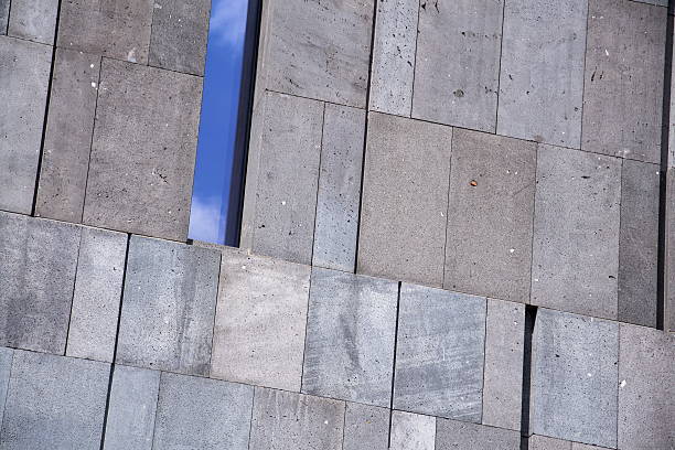 Narrow window reflecting blue sky on modern concrete office building