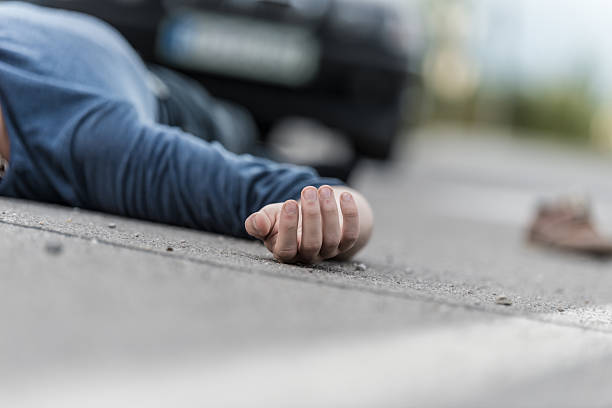 Car hit scene, male person lying on the floor in front of a car