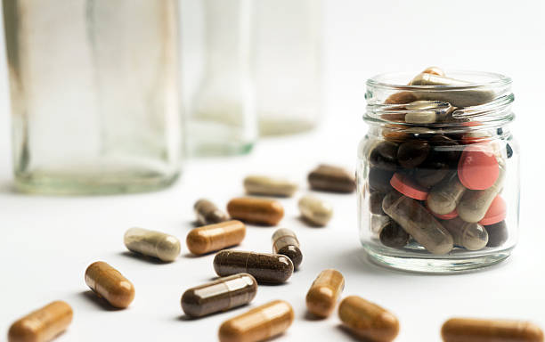 istock Different pills and capsules in glass jar on white background. 523497880