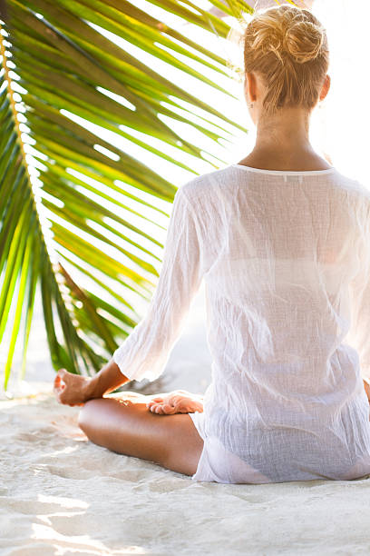 istock Young woman sitting on the  beach and meditating 523500074