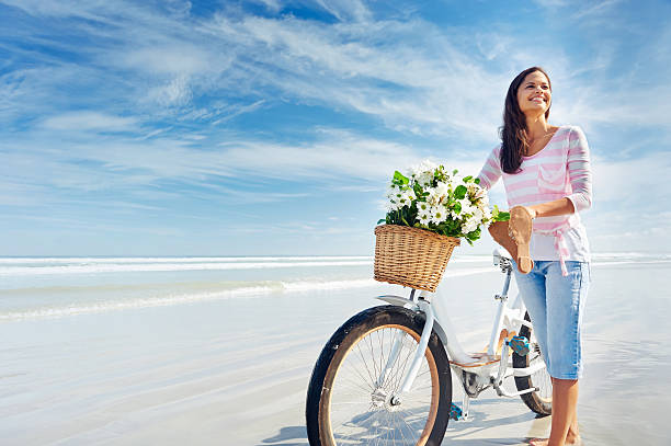 woman with bicycle and flowers in basket smiling carefree and happy