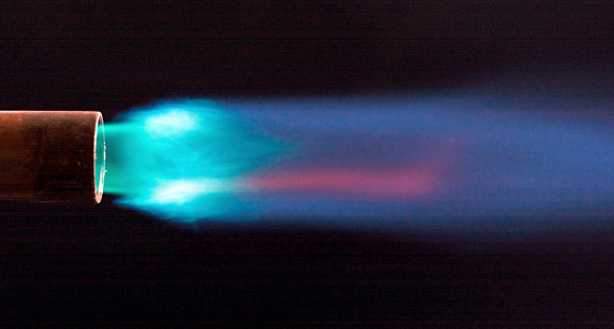 A lighted propane torch showing the flame on a dark black background.