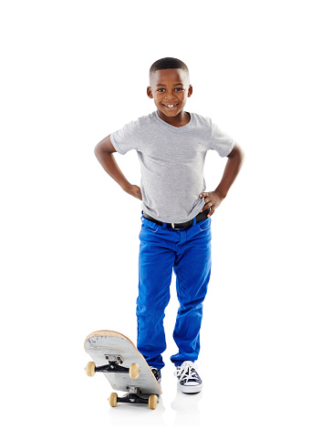 Studio shot of a cute little boy posing with his skateboard against a white background