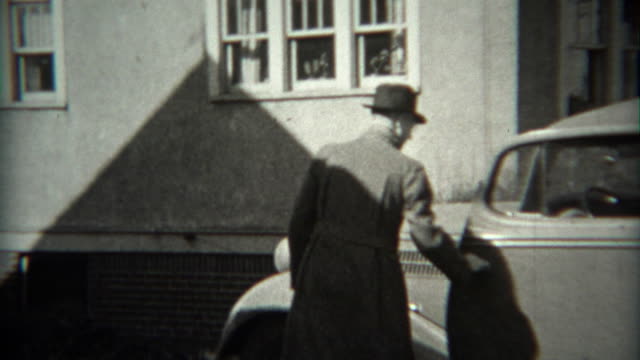 1936: Man backing car out of driveway in Ford 1934 model vehicle.