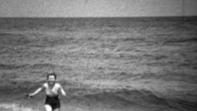 1936: Women in swimsuit scared of swimming in ocean waves.