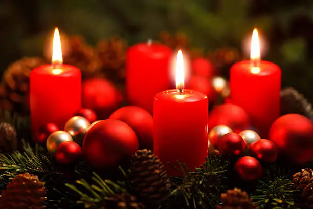 Low-key studio shot of a nice advent wreath with baubles and three burning red candles
