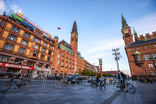 Copenhagen City Hall Square, Denmark Copenhagen, Denmark  - September 10, 2014: Copenhagen City Hall Square, Denmark. Two young men standing on the square with their bicycles and talking town hall square copenhagen stock pictures, royalty-free photos & images