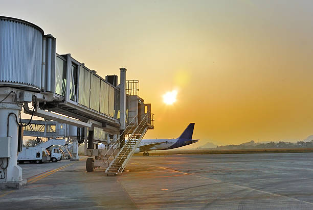 aerobridge estacionados no aeroporto ao pôr do sol - fotografia de stock