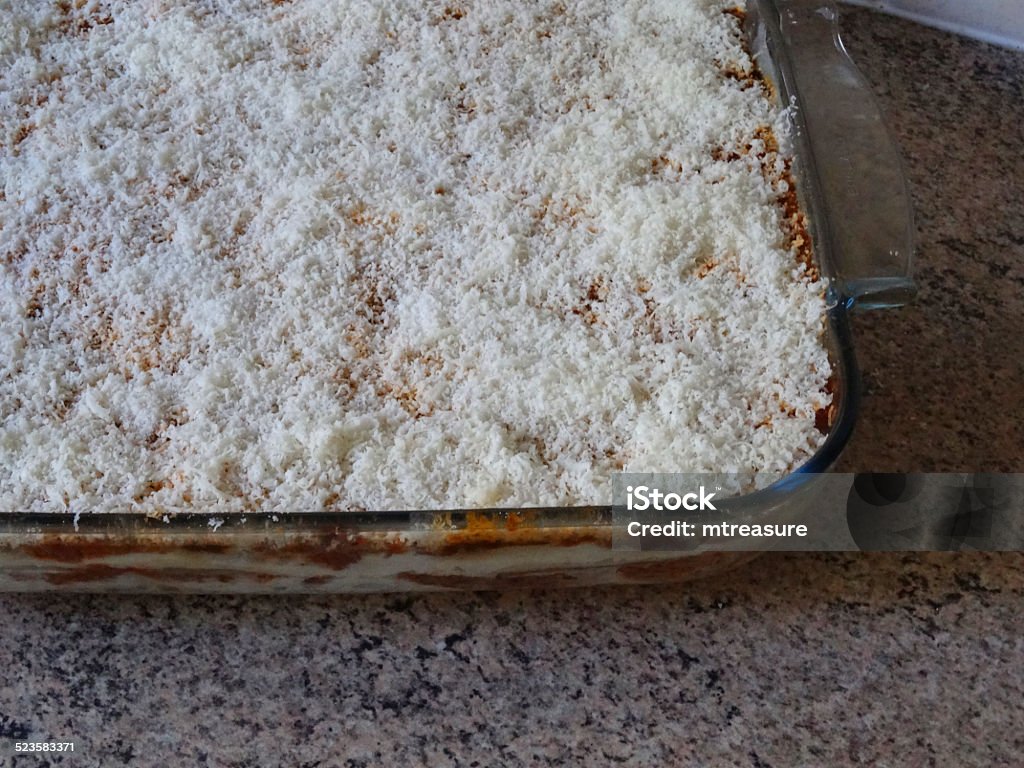 Prepared homemade lasagne image / glass lasagna dish, grated parmesan cheese Photo showing a homemade lasagne meal in a square glass lasagna dish, with bolognese and pasta layers, topped with a bechamel sauce / white sauce and finely grated parmesan cheese.  The lasagne has just been prepared and is ready to be cooked in the oven. Bechamel Sauce Stock Photo