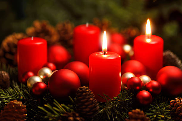 Advent wreath with 2 burning candles Low-key studio shot of a nice advent wreath with baubles and two burning red candles christmas ornament christmas decoration red religious celebration stock pictures, royalty-free photos & images