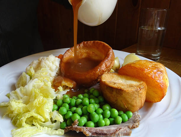 istock Sunday roast dinner, beef, Yorkshire pudding, pouring gravy jug, roast potatoes 523595089