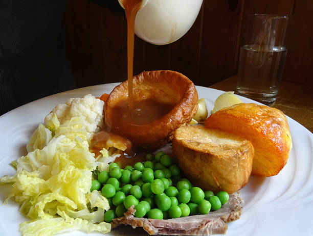 niedzielny obiad pieczeń wołowiny i yorkshire pudding, wlewając-sos, pieczeń-ziemniaki, warzywa, marchew i groszkiem-kapusta-kalafior-nadzienie - yorkshire pudding zdjęcia i obrazy z banku zdjęć