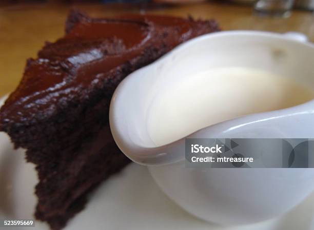 Homemade Chocolate Fudge Cake Slice Jug Of Cream Ganache Buttericing Stock Photo - Download Image Now