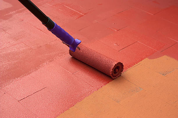 contrato artista pintando un piso en color rojo - impermeable fotografías e imágenes de stock