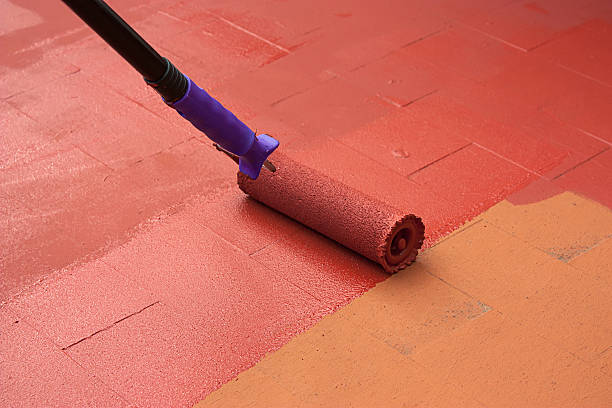 Contract painter painting a floor on color red Contract painter painting a floor on color red for waterproofing. He is using a paint roller. waterproof stock pictures, royalty-free photos & images