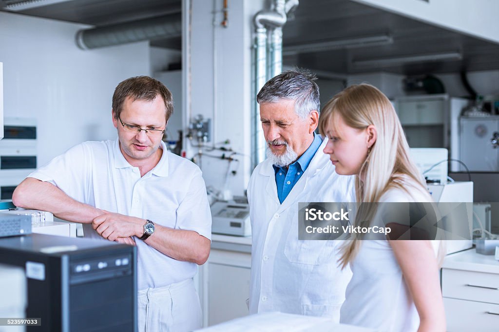 Team of researchers carrying out experiments Team of researchers carrying out experiments in a lab (shallow DOF; color toned image) Laboratory Stock Photo