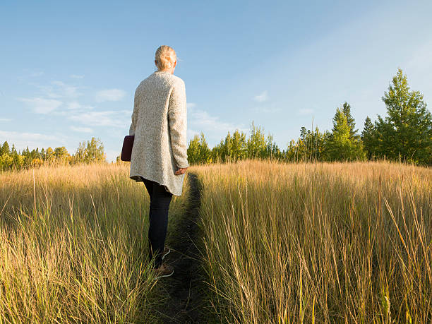 istock Woman follows path through grasses, holding digital tablet 523613469