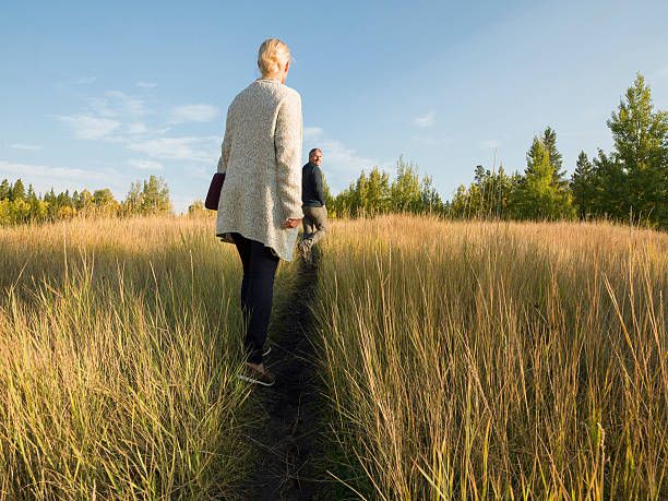 istock Couple follow path through grasses, holding digital tablet 523613475
