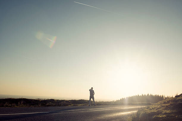 istock Man walking along an empty country road in afternoon sunshine 523614250