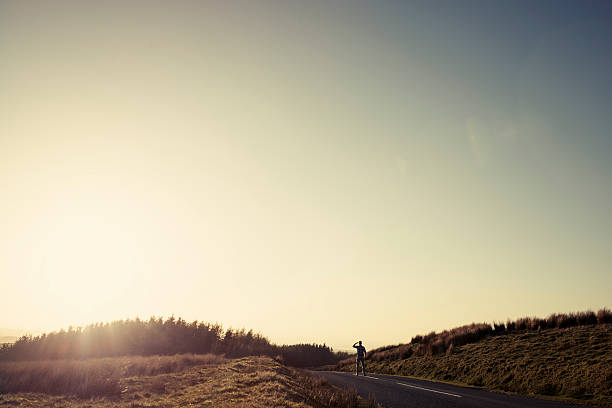 istock Man walking along an empty country road in afternoon sunshine 523614396