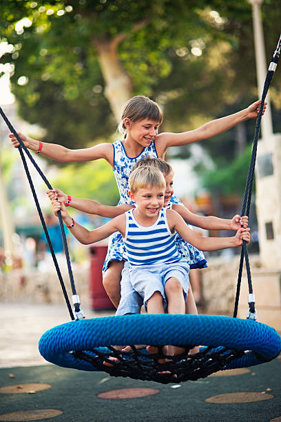 Three kids having fun swinging on a giant swing. Sister is 9 and her two brothers are 5,