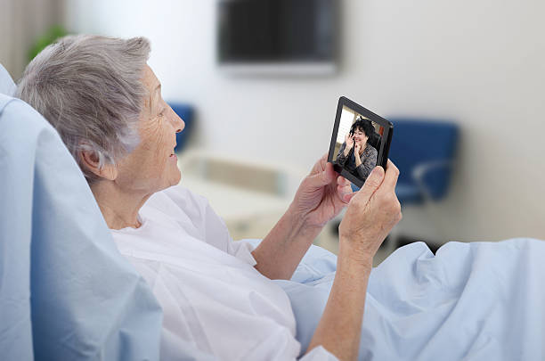 Old woman in hospital ward has video chat stock photo