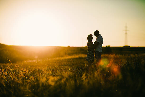istock Romantic couple standing and kissing on background summer meadow sunset 523628886