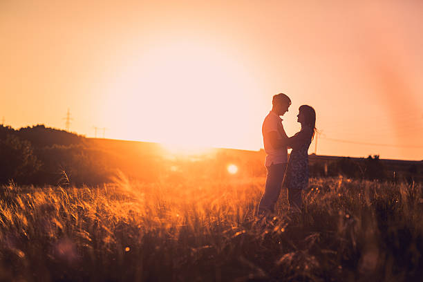 istock Romantic couple standing and kissing on background summer meadow sunset 523628930