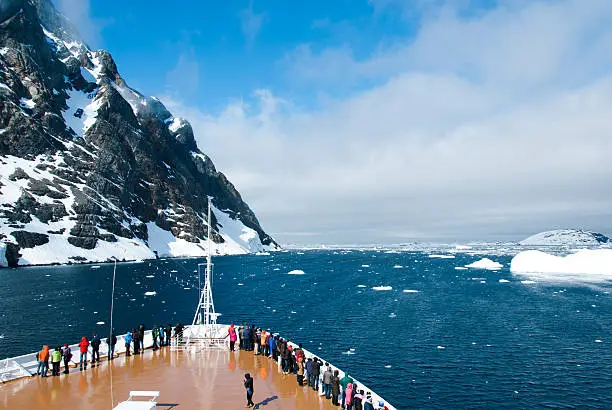 Cruise ship in Antarctica in sunny day passing the mountains and glaciers