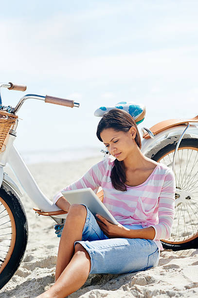istock beach bicycle tablet woman 523631899